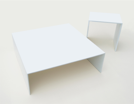 Two minimalist white tables have a square top with its sides forming right angles. The smaller table stands taller.
